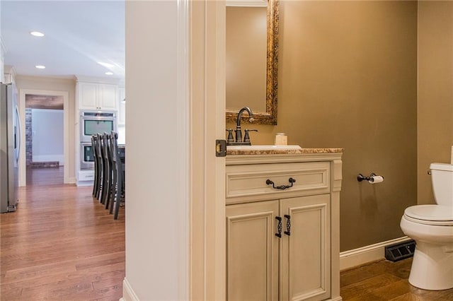 bathroom with hardwood / wood-style floors, vanity, toilet, and crown molding