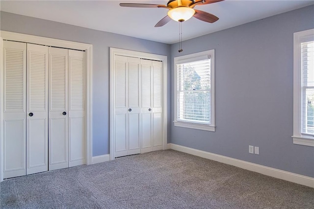 unfurnished bedroom with multiple closets, ceiling fan, and carpet floors