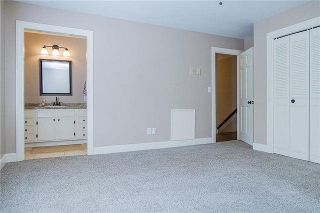 unfurnished bedroom featuring light carpet, connected bathroom, and sink