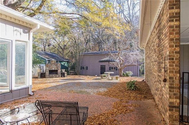 view of patio / terrace featuring an outdoor stone fireplace and a storage unit