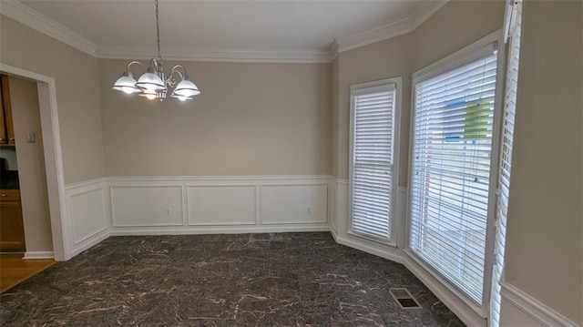 unfurnished dining area featuring visible vents, crown molding, a wainscoted wall, an inviting chandelier, and a decorative wall