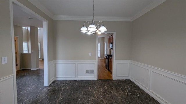 unfurnished dining area featuring a wainscoted wall, visible vents, crown molding, a notable chandelier, and marble finish floor