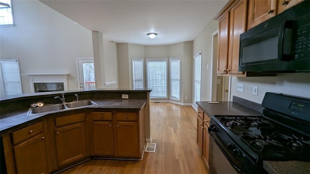 kitchen with dark countertops, black microwave, range with gas stovetop, brown cabinetry, and a sink