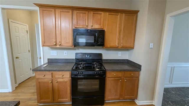 kitchen featuring black appliances, brown cabinetry, and light wood-type flooring