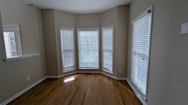 spare room featuring visible vents, baseboards, and wood finished floors