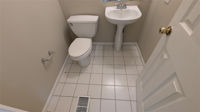 half bath featuring tile patterned flooring, visible vents, toilet, and baseboards