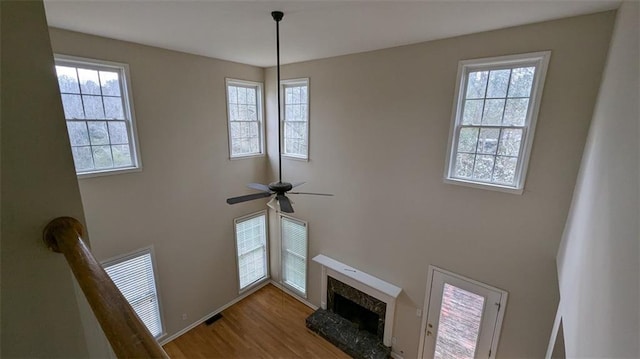 details featuring ceiling fan, visible vents, wood finished floors, and a fireplace