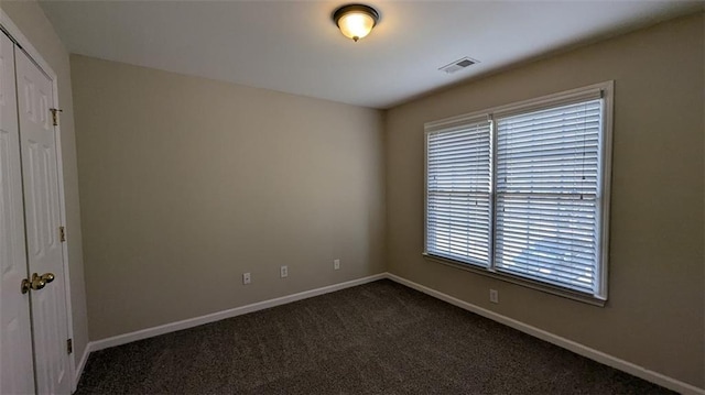 unfurnished bedroom featuring a closet, baseboards, visible vents, and dark colored carpet