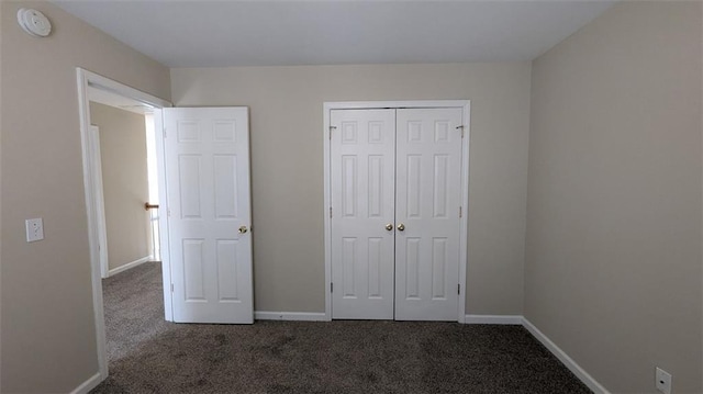 unfurnished bedroom featuring a closet, baseboards, and carpet floors