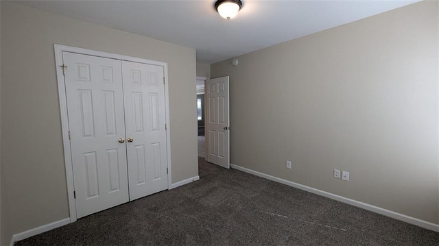 unfurnished bedroom featuring a closet, dark carpet, and baseboards