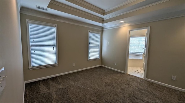 carpeted empty room featuring a tray ceiling, visible vents, baseboards, and ornamental molding