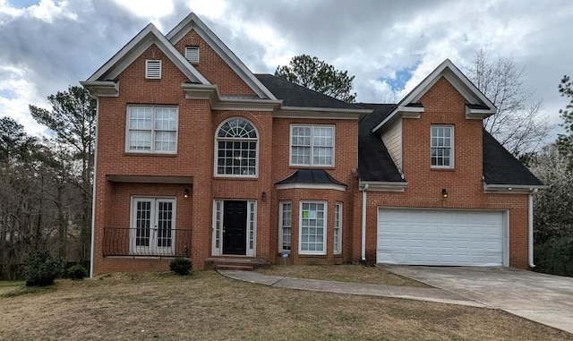 view of front facade featuring a front yard, roof with shingles, concrete driveway, french doors, and brick siding