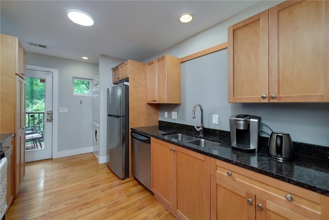 2023 Oakview Rd SE Unit 226, Atlanta, GA 30317 - kitchen featuring stainless steel appliances, stacked washer and clothes dryer, light wood-style flooring, dark stone countertops, and recessed lighting