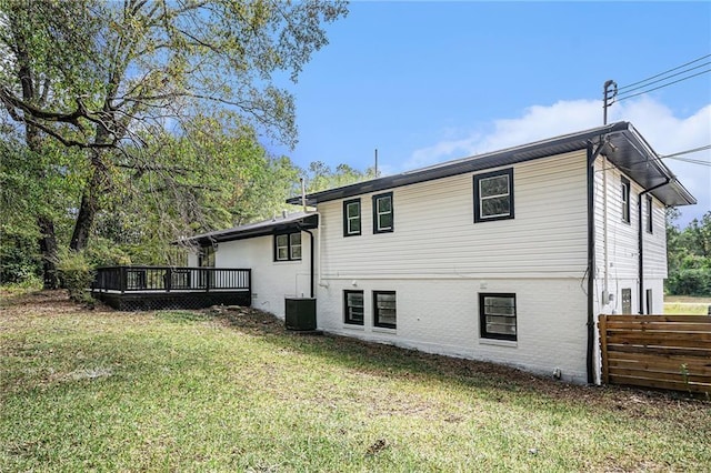 back of property featuring a lawn, fence, a wooden deck, central AC, and brick siding