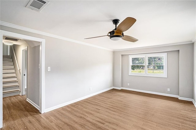 spare room featuring crown molding, wood finished floors, visible vents, and baseboards