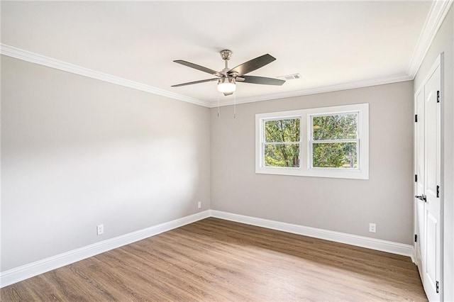 spare room featuring ornamental molding, visible vents, baseboards, and wood finished floors