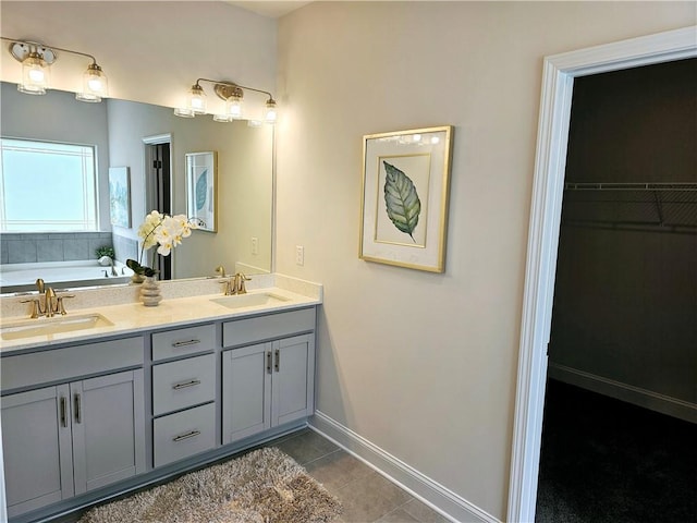 bathroom featuring tile patterned flooring, double vanity, baseboards, and a sink