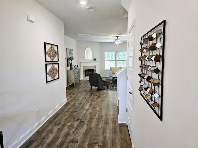 hallway featuring dark wood finished floors, visible vents, and baseboards