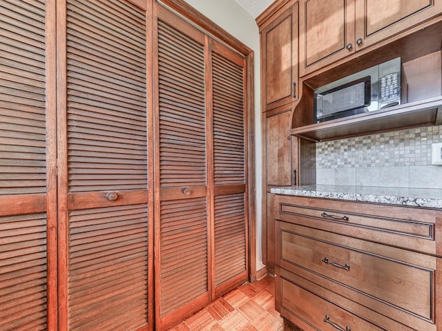 kitchen featuring light stone countertops, a textured ceiling, backsplash, and light parquet floors