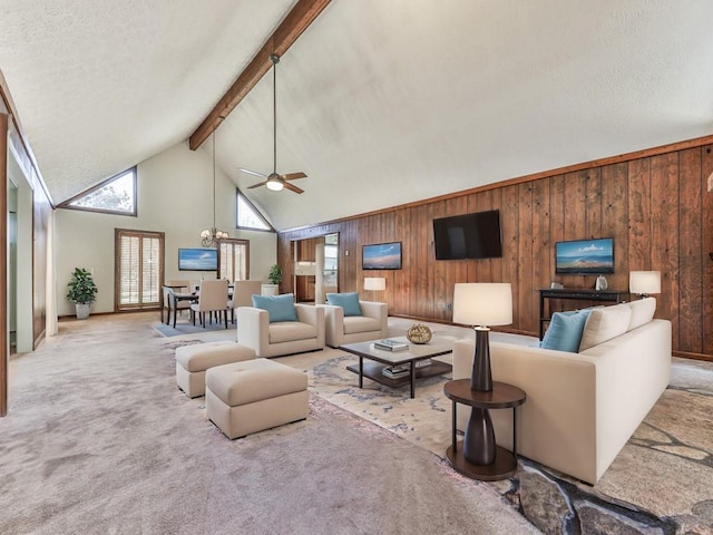 living room featuring high vaulted ceiling, ceiling fan with notable chandelier, wooden walls, beam ceiling, and light colored carpet