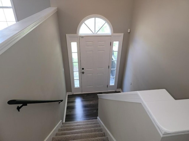 foyer entrance featuring stairway, baseboards, and dark wood-style flooring