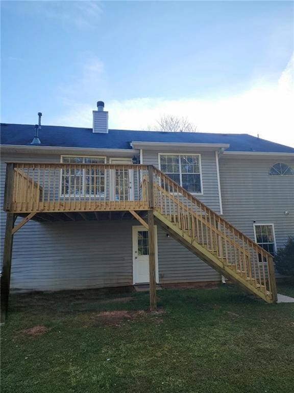 rear view of house with a deck, stairway, a lawn, and a chimney