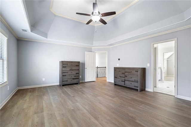 unfurnished bedroom with ceiling fan, ornamental molding, multiple windows, and a tray ceiling