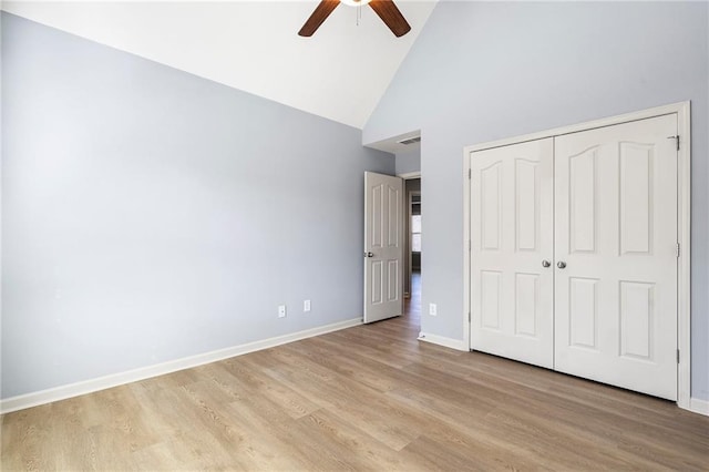 unfurnished bedroom featuring ceiling fan, light hardwood / wood-style flooring, high vaulted ceiling, and a closet