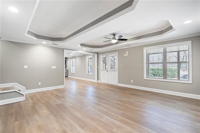 unfurnished living room with light wood-type flooring, a tray ceiling, ceiling fan, and crown molding