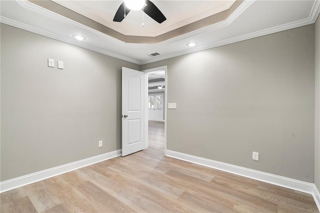 empty room with ceiling fan, light wood-type flooring, ornamental molding, and a tray ceiling