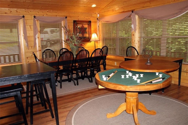 dining space featuring wooden walls, vaulted ceiling, wood ceiling, and wood-type flooring