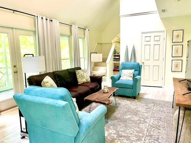 living room with lofted ceiling, french doors, and light wood-type flooring