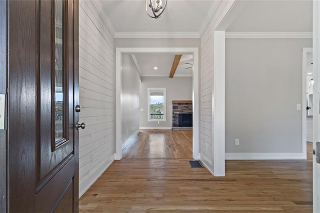 entryway featuring crown molding, light wood-style flooring, a fireplace, and baseboards