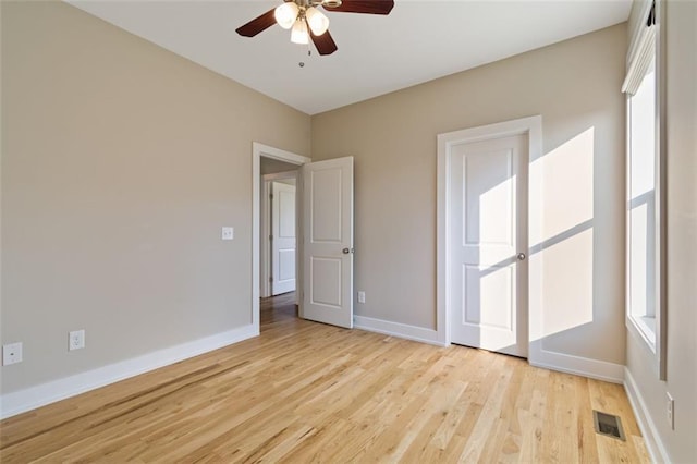 unfurnished bedroom with visible vents, light wood-style flooring, baseboards, and multiple windows