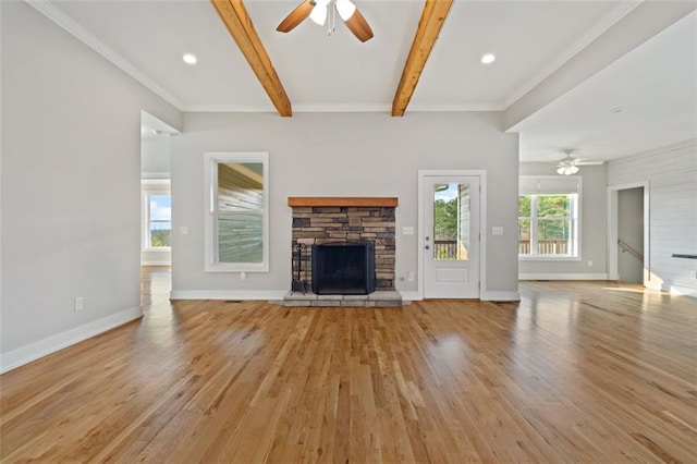 unfurnished living room featuring light wood-type flooring, beamed ceiling, a stone fireplace, and ceiling fan