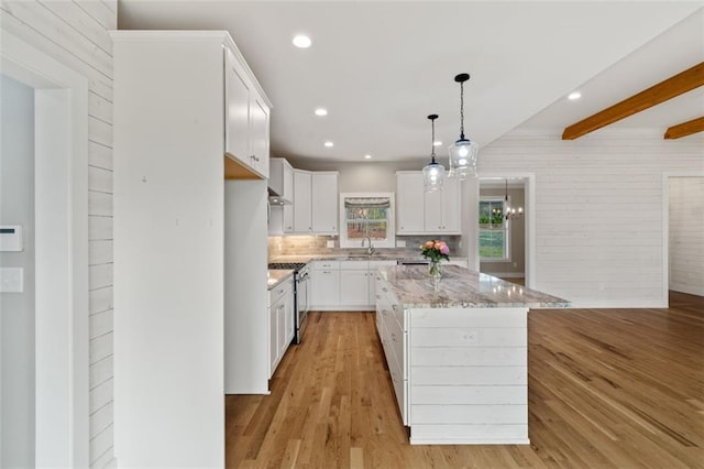 kitchen featuring light wood-style flooring, backsplash, a center island, white cabinetry, and stainless steel range with gas stovetop