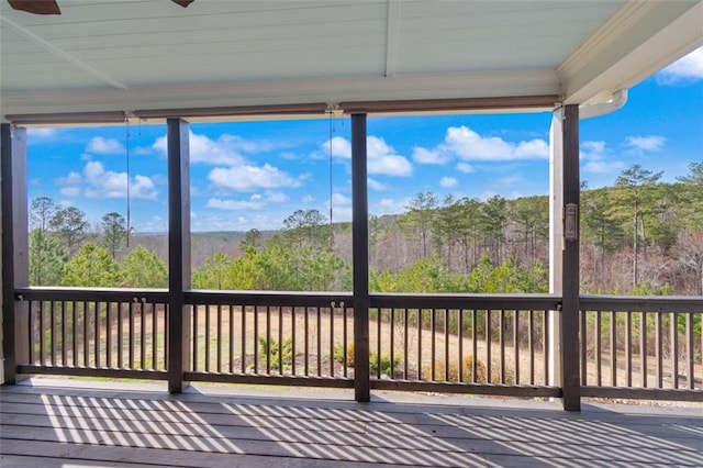 unfurnished sunroom with a wooded view and ceiling fan