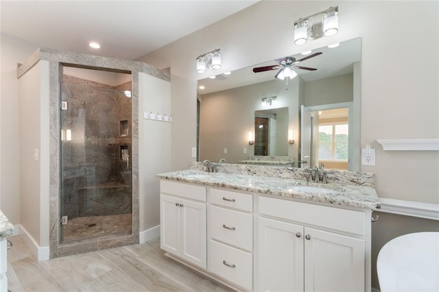 bathroom featuring a sink, double vanity, a stall shower, and a ceiling fan