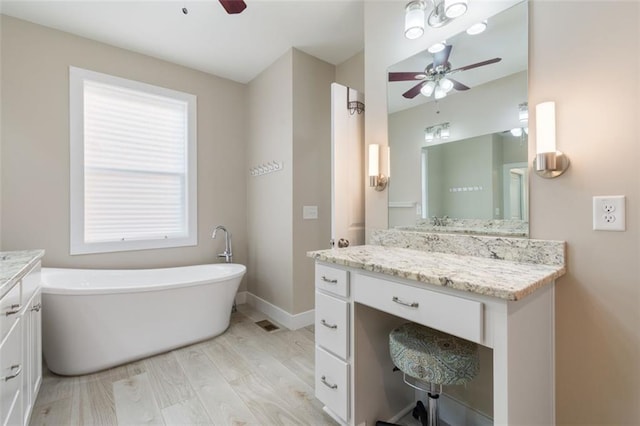 full bathroom featuring baseboards, ceiling fan, a freestanding bath, wood finished floors, and vanity