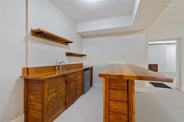 bar with a sink, baseboards, wet bar, and dishwasher