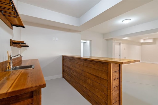 bar with bar, baseboards, and a sink