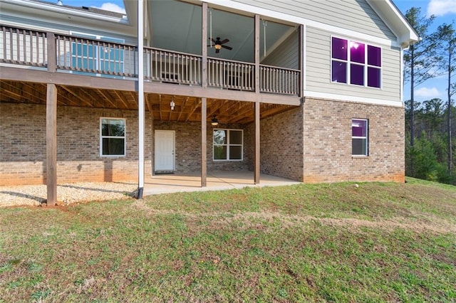 back of property featuring brick siding, a lawn, a ceiling fan, and a patio