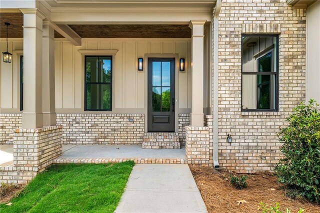 7262 Creekside Way, Jefferson, GA 30549 - doorway to property featuring board and batten siding, covered porch, and brick siding