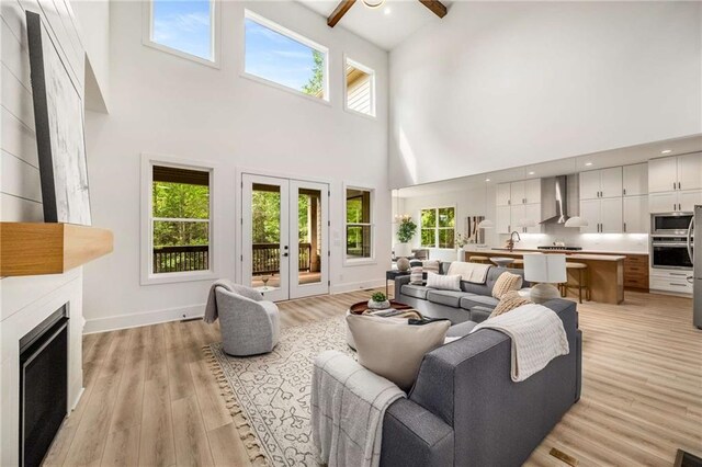7262 Creekside Way, Jefferson, GA 30549 - living room featuring a towering ceiling, a ceiling fan, a fireplace, light wood-style flooring, and french doors