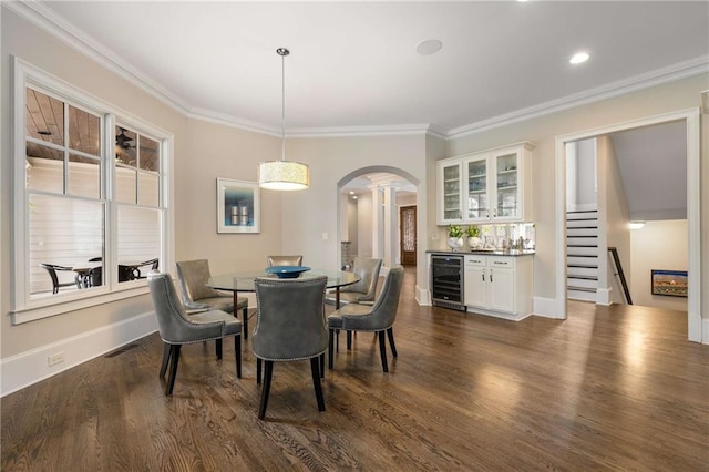 dining space featuring arched walkways, wine cooler, dark wood-type flooring, ornamental molding, and a bar