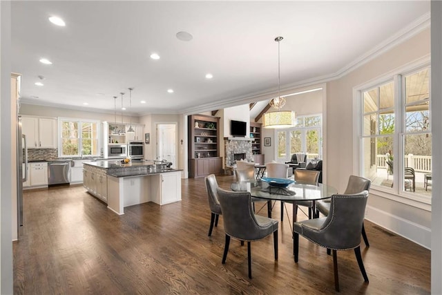 dining space featuring crown molding, a wealth of natural light, and a stone fireplace