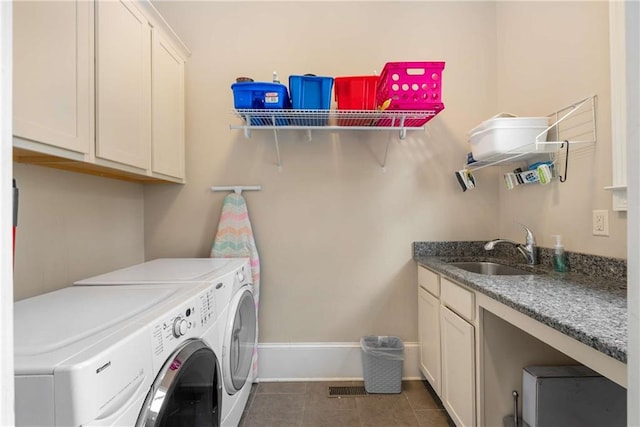 laundry area featuring dark tile patterned flooring, cabinet space, a sink, washer and dryer, and baseboards