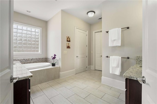 bathroom featuring visible vents, vanity, baseboards, and a bath