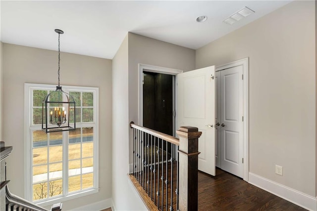 hallway with a chandelier, an upstairs landing, visible vents, baseboards, and dark wood-style floors