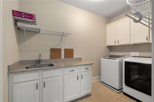 laundry area with light tile patterned floors, cabinet space, a sink, washer and dryer, and baseboards